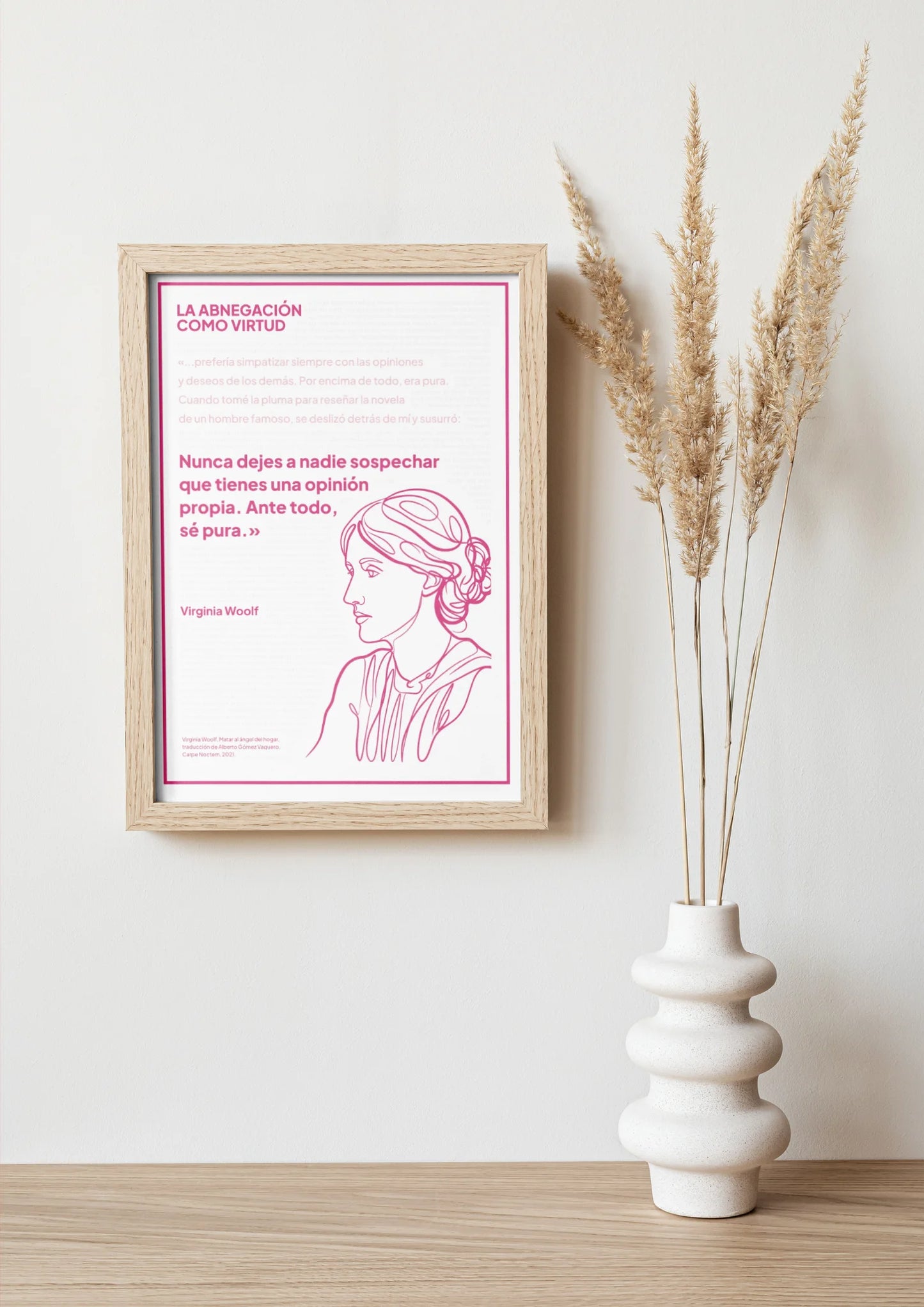 Afiche magenta de Virginia Woolf enmarcado sobre una repisa con jarrón y ramas secas.