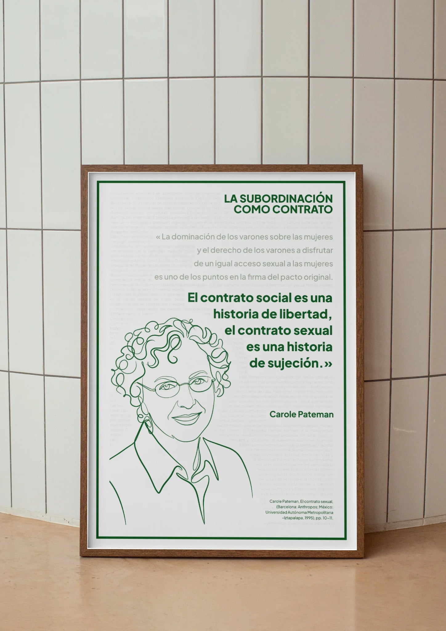 Afiche verde de Carole Pateman enmarcado frente a un muro de azulejos claros.