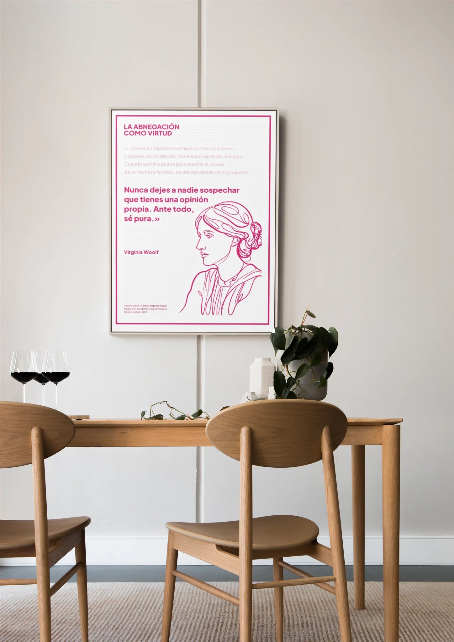 Afiche magenta de Virginia Woolf enmarcado sobre una mesa de comedor de madera.