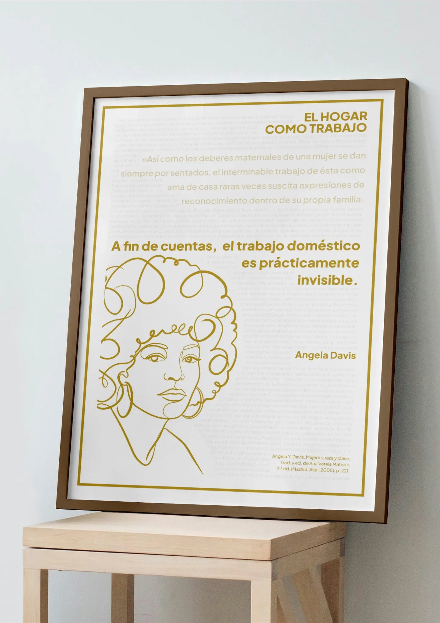 Afiche dorado de Angela Davis enmarcado, apoyado sobre un banco de madera clara.